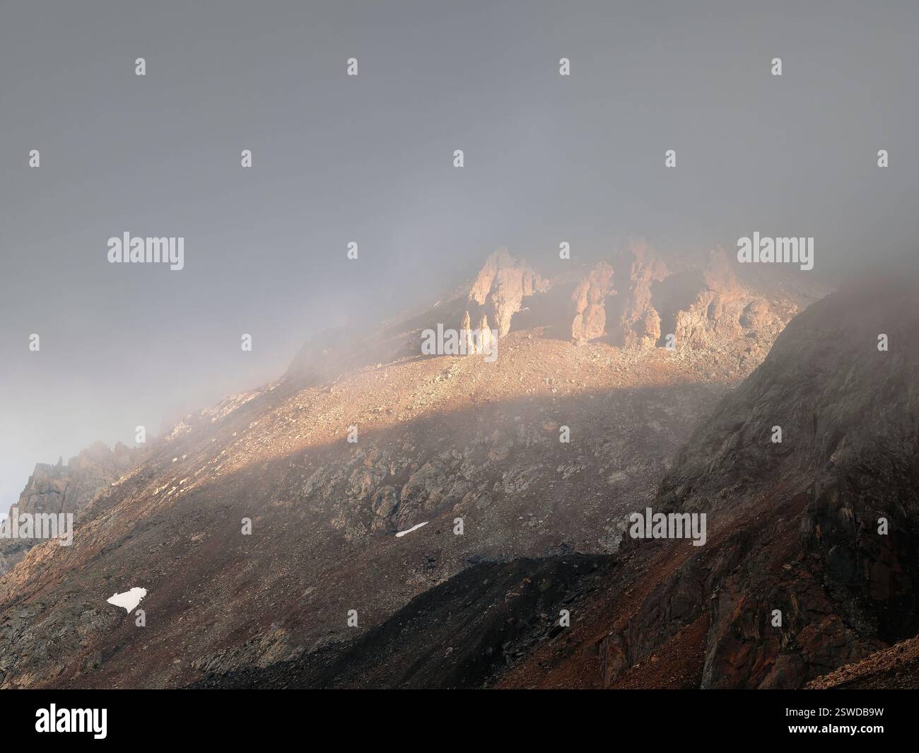 Paysage fantomatique atmosphérique avec des silhouettes floues de roches acérées dans des nuages bas. Vue spectaculaire sur les grandes montagnes floues en R. Banque D'Images