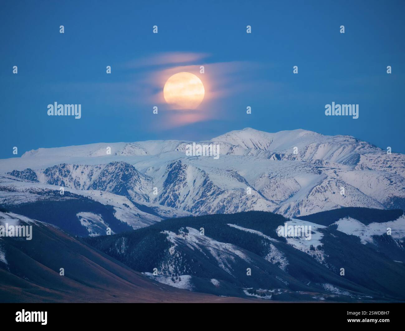 Grande lune au-dessus d'une montagne enneigée. La nuit remplace le jour de pleine lune. Banque D'Images Grande lune au-dessus d'une montagne enneigée. La nuit remplace le jour de pleine lune. Banque D'Images