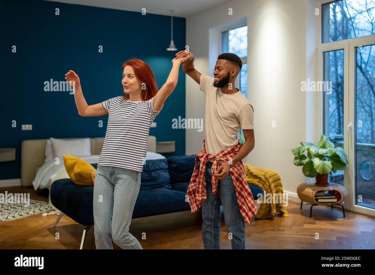 Joyeux couple multiracial romantique en amour apprenant à danser ensemble à la maison Banque D'Images