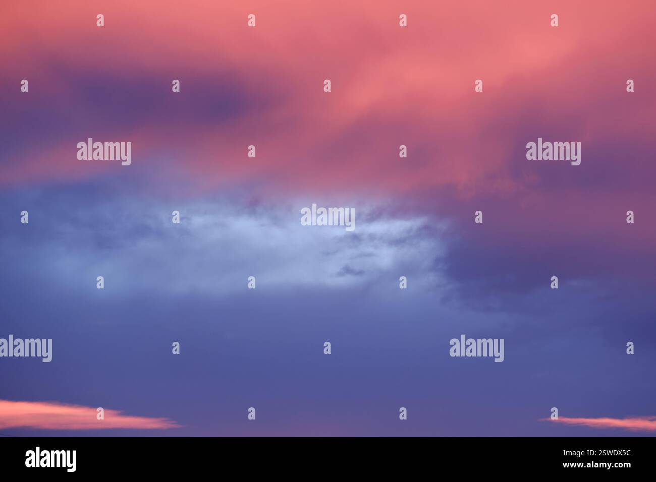 Les teintes pastel du coucher de soleil peignent le ciel avec de doux nuages roses et violets Banque D'Images