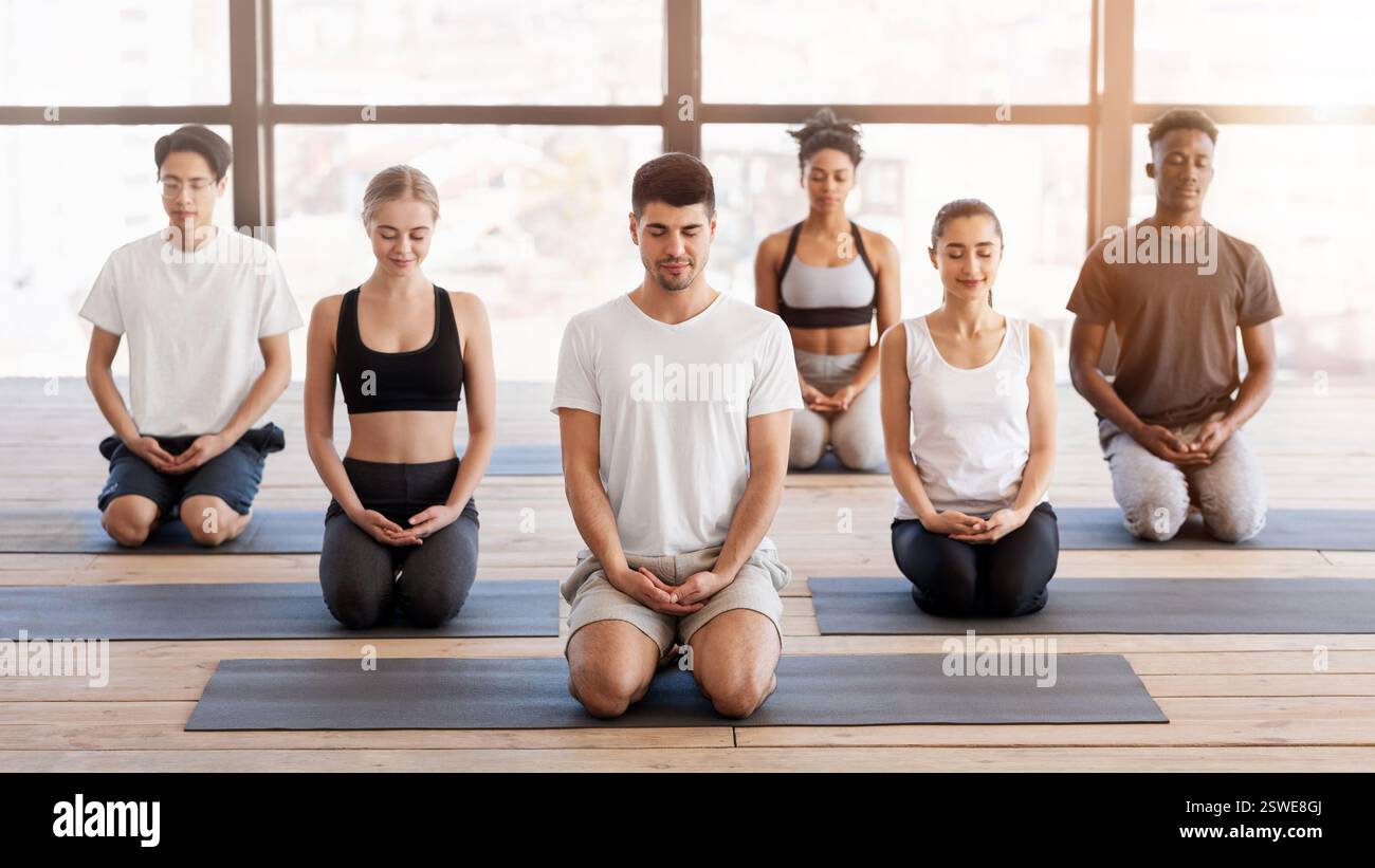 Méditation de groupe. Les personnes pratiquant des exercices de yoga de respiration avec instructeur dans le studio Banque D'Images