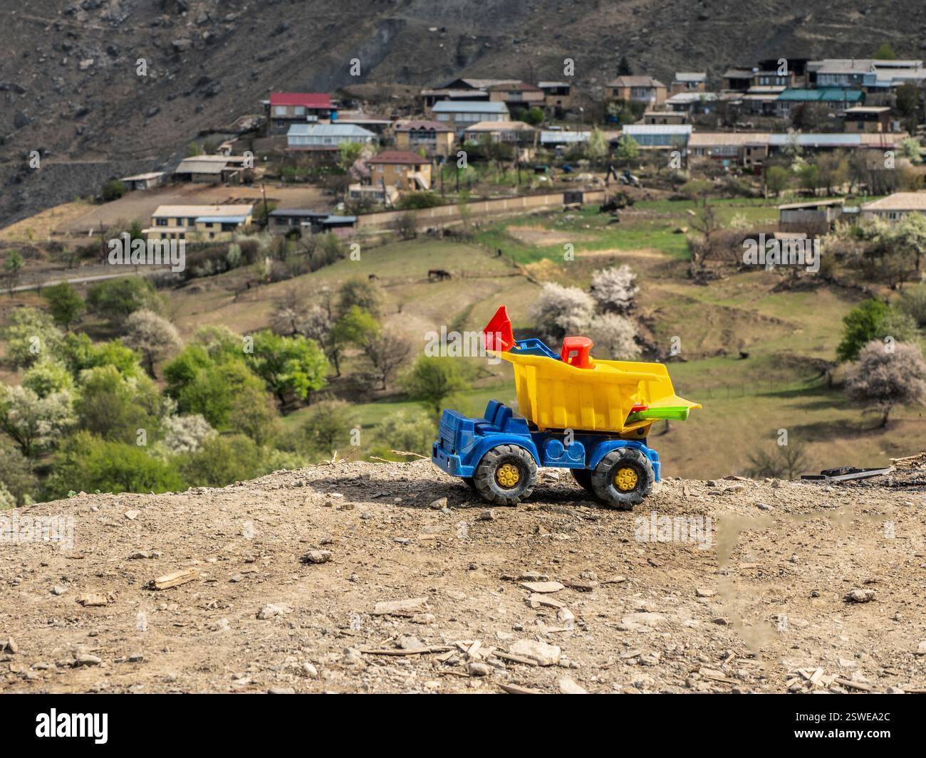 Camion à benne sale jaune jouet sur le fond d'un paysage de montagne. Banque D'Images
