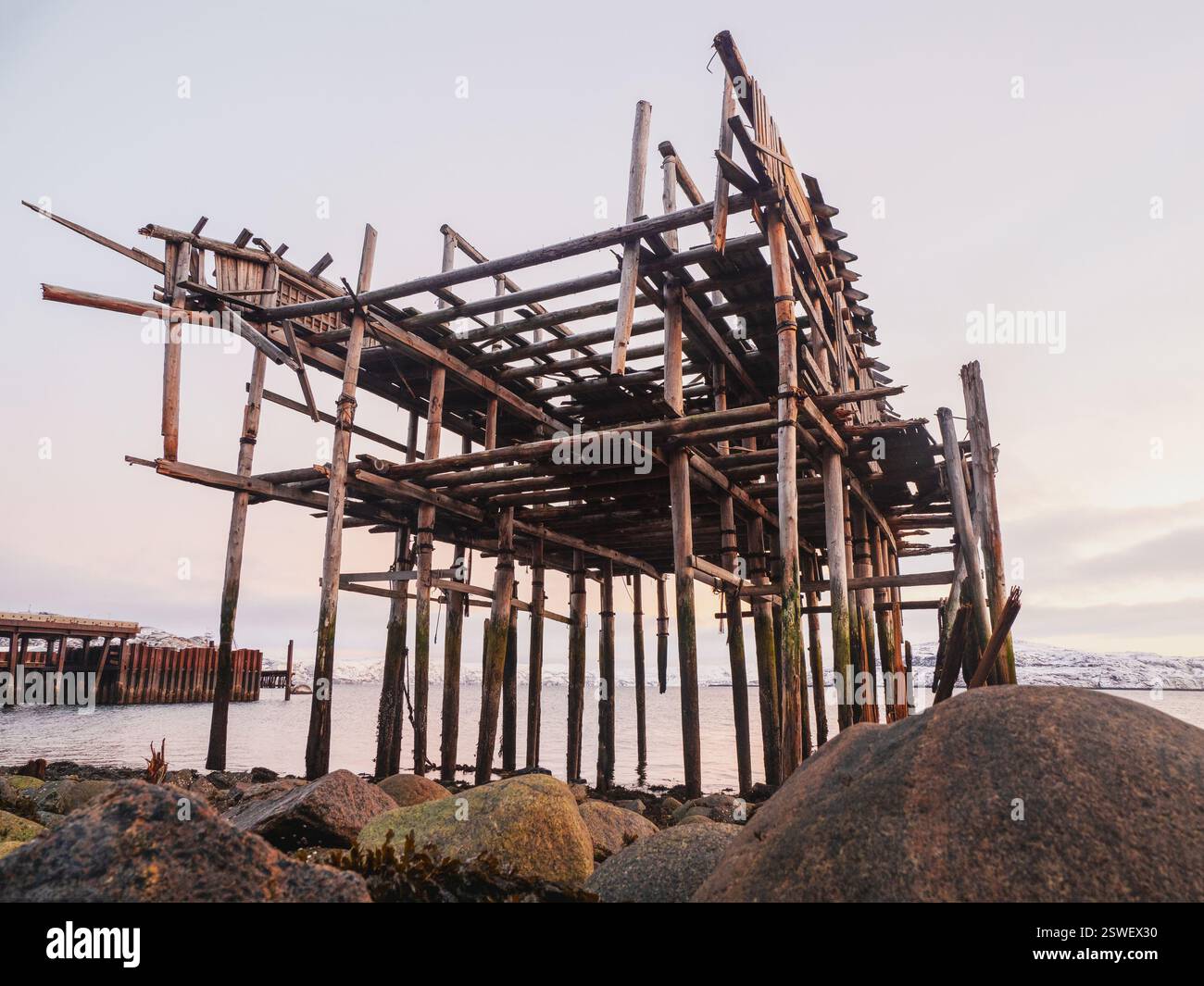 Le squelette d'un hangar de pêche sur la plage. Maison abandonnée contre le ciel arctique. Ancien village authentique de Teriberka. Banque D'Images
