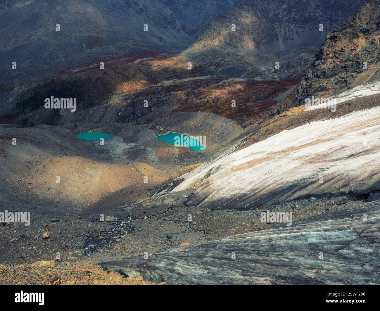 Chiaroscuro de montagne. Impressionnant paysage montagneux dans l'obscurité avec une énorme montagne enneigée et un glacier illuminé par le soleil amo Banque D'Images