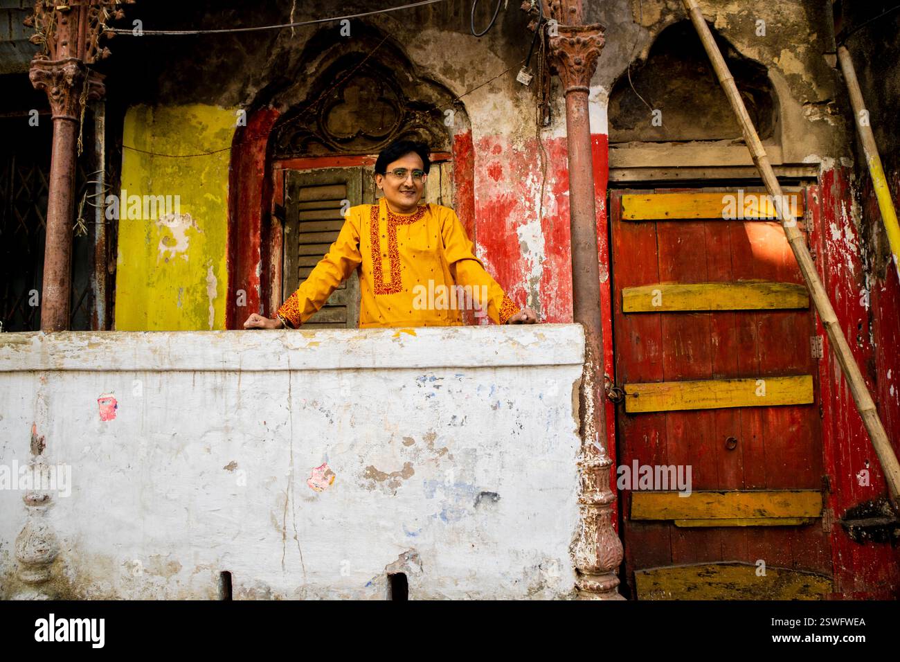 Un indien portant un dhoti rouge bengali traditionnel indien et kurta orange posant en plein air dans les rues de kolkata Banque D'Images