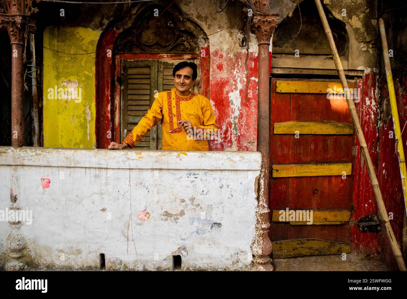 Un indien portant un dhoti rouge bengali traditionnel indien et kurta orange posant en plein air dans les rues de kolkata Banque D'Images