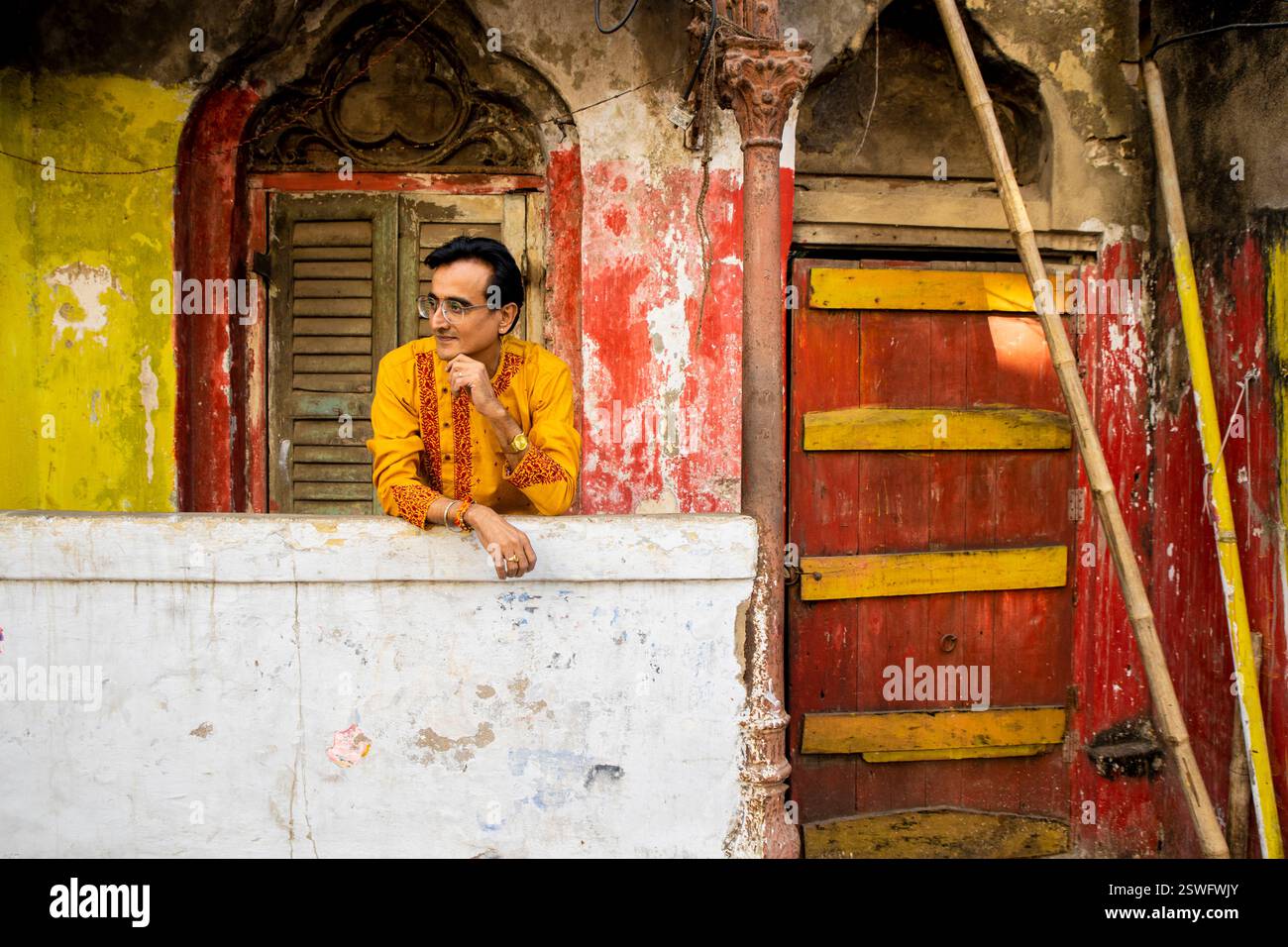 Un indien portant un dhoti rouge bengali traditionnel indien et kurta orange posant en plein air dans les rues de kolkata Banque D'Images
