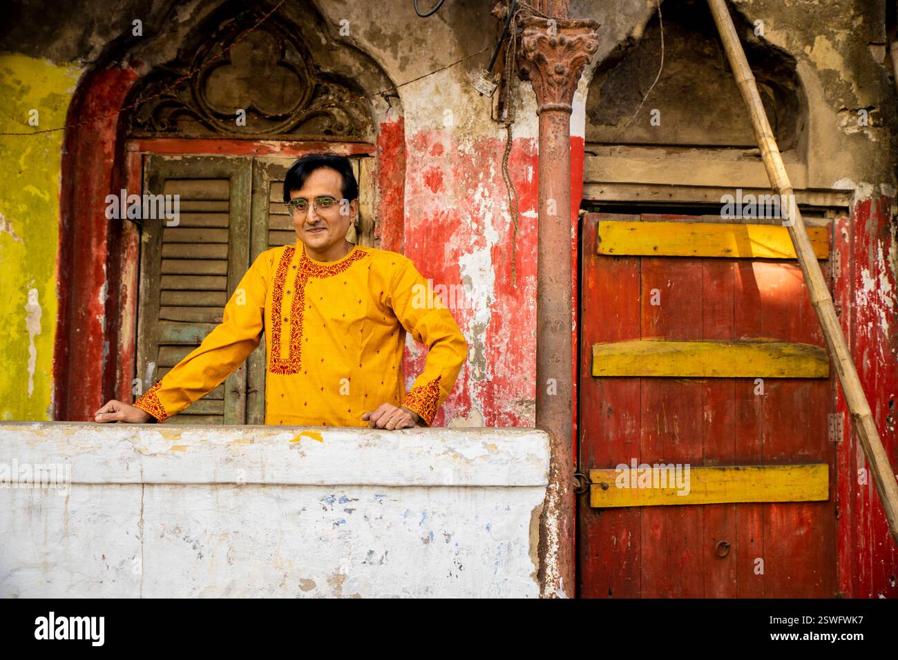 Un indien portant un dhoti rouge bengali traditionnel indien et kurta orange posant en plein air dans les rues de kolkata Banque D'Images
