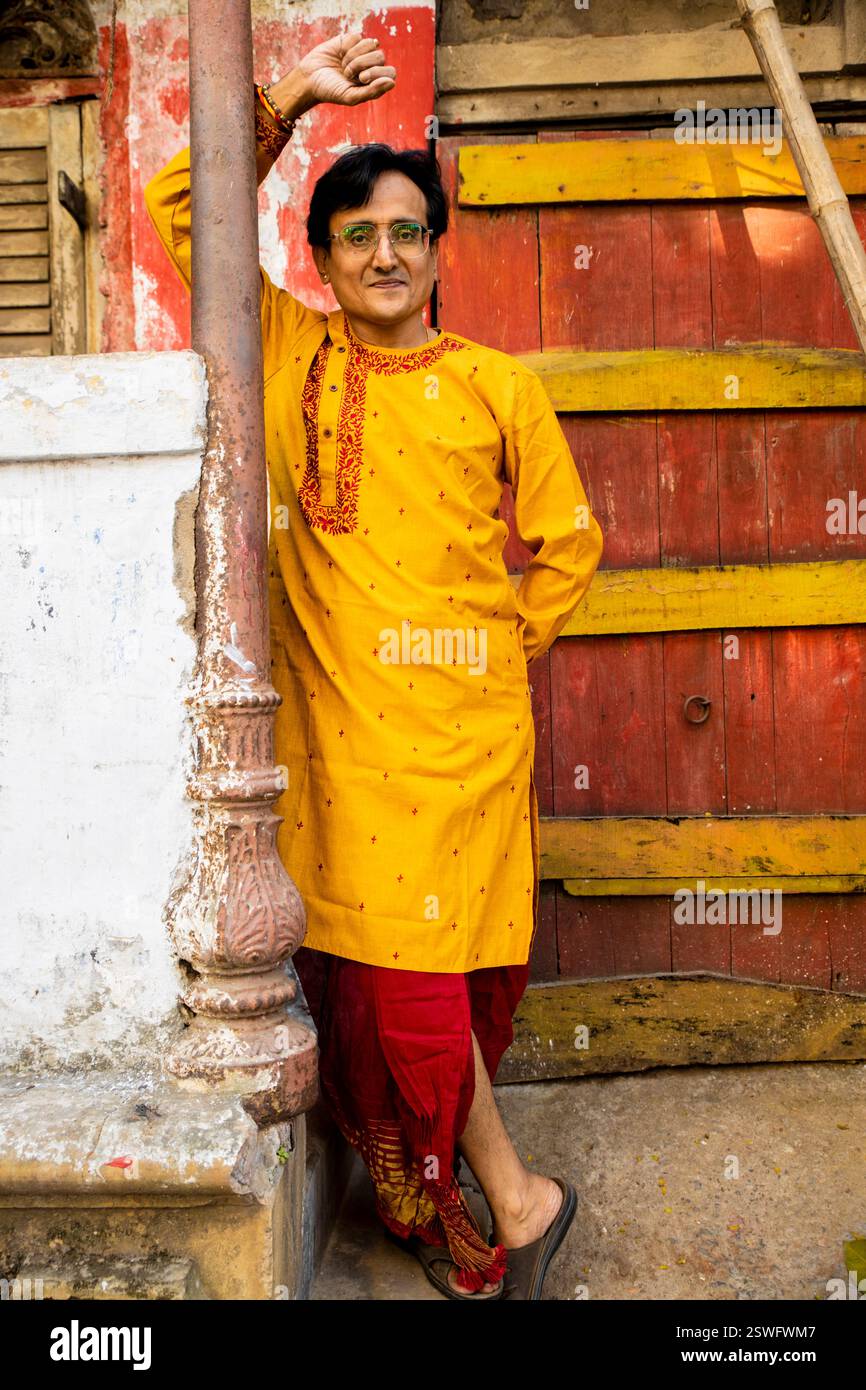 Un indien portant un dhoti rouge bengali traditionnel indien et kurta orange posant en plein air dans les rues de kolkata Banque D'Images