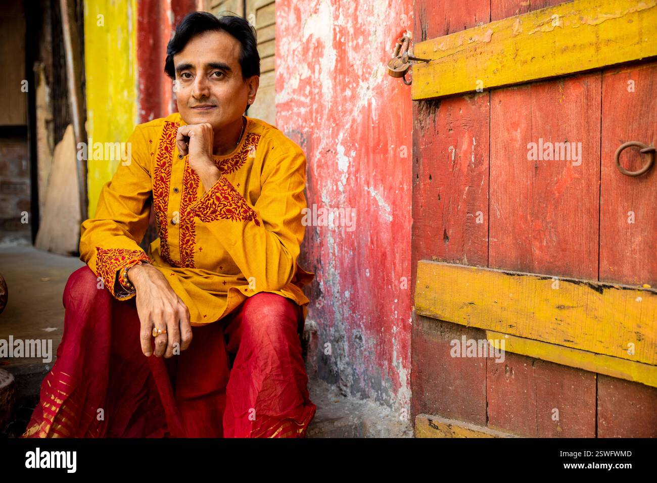 Un indien portant un dhoti rouge bengali traditionnel indien et kurta orange posant en plein air dans les rues de kolkata Banque D'Images