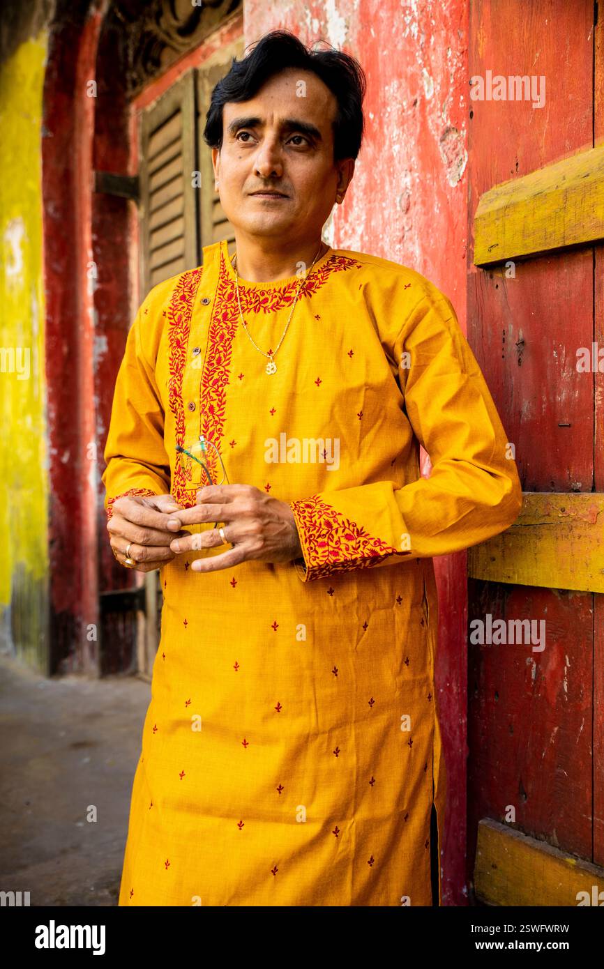 Un indien portant un dhoti rouge bengali traditionnel indien et kurta orange posant en plein air dans les rues de kolkata Banque D'Images