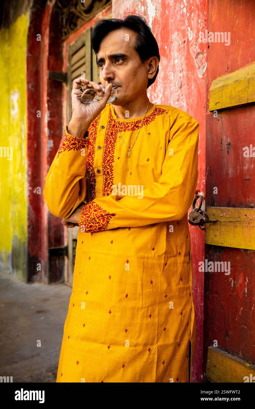 Un indien portant un dhoti rouge bengali traditionnel indien et kurta orange posant en plein air dans les rues de kolkata Banque D'Images