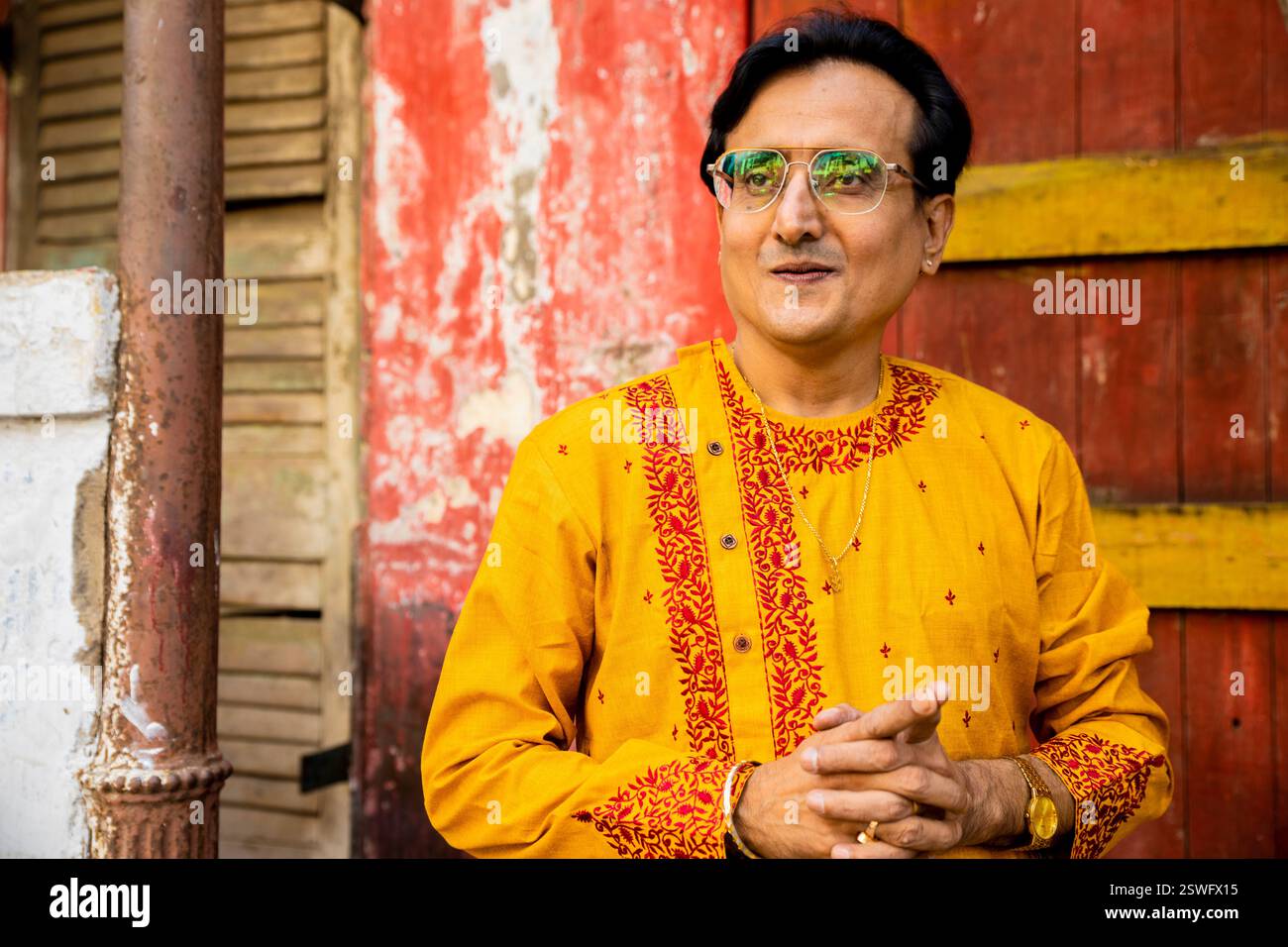 Un indien portant un dhoti rouge bengali traditionnel indien et kurta orange posant en plein air dans les rues de kolkata Banque D'Images