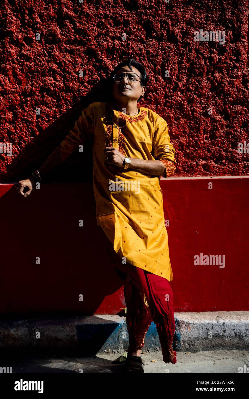 Un indien portant un dhoti rouge bengali traditionnel indien et kurta orange posant en plein air dans les rues de kolkata Banque D'Images