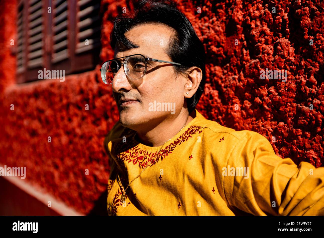 Un indien portant un dhoti rouge bengali traditionnel indien et kurta orange posant en plein air dans les rues de kolkata Banque D'Images