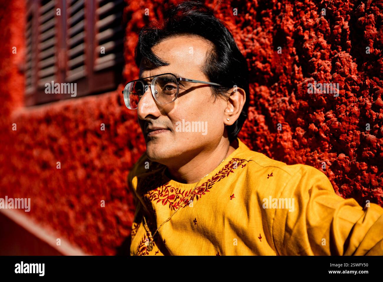 Un indien portant un dhoti rouge bengali traditionnel indien et kurta orange posant en plein air dans les rues de kolkata Banque D'Images