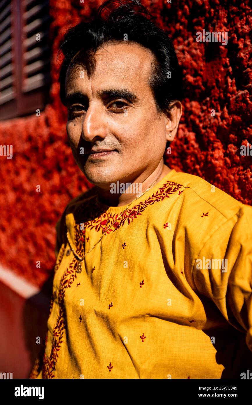 Un indien portant un dhoti rouge bengali traditionnel indien et kurta orange posant en plein air dans les rues de kolkata Banque D'Images