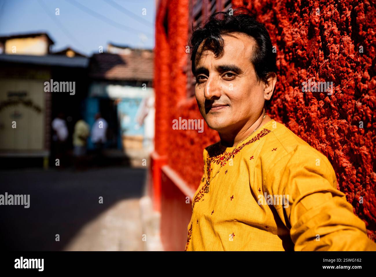 Un indien portant un dhoti rouge bengali traditionnel indien et kurta orange posant en plein air dans les rues de kolkata Banque D'Images
