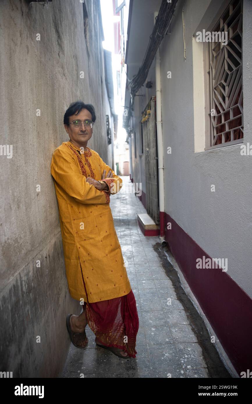 Un indien portant un dhoti rouge bengali traditionnel indien et kurta orange posant en plein air dans les rues de kolkata Banque D'Images