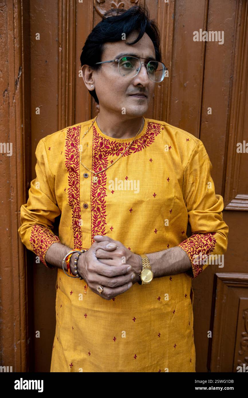 Un indien portant un dhoti rouge bengali traditionnel indien et kurta orange posant en plein air dans les rues de kolkata Banque D'Images