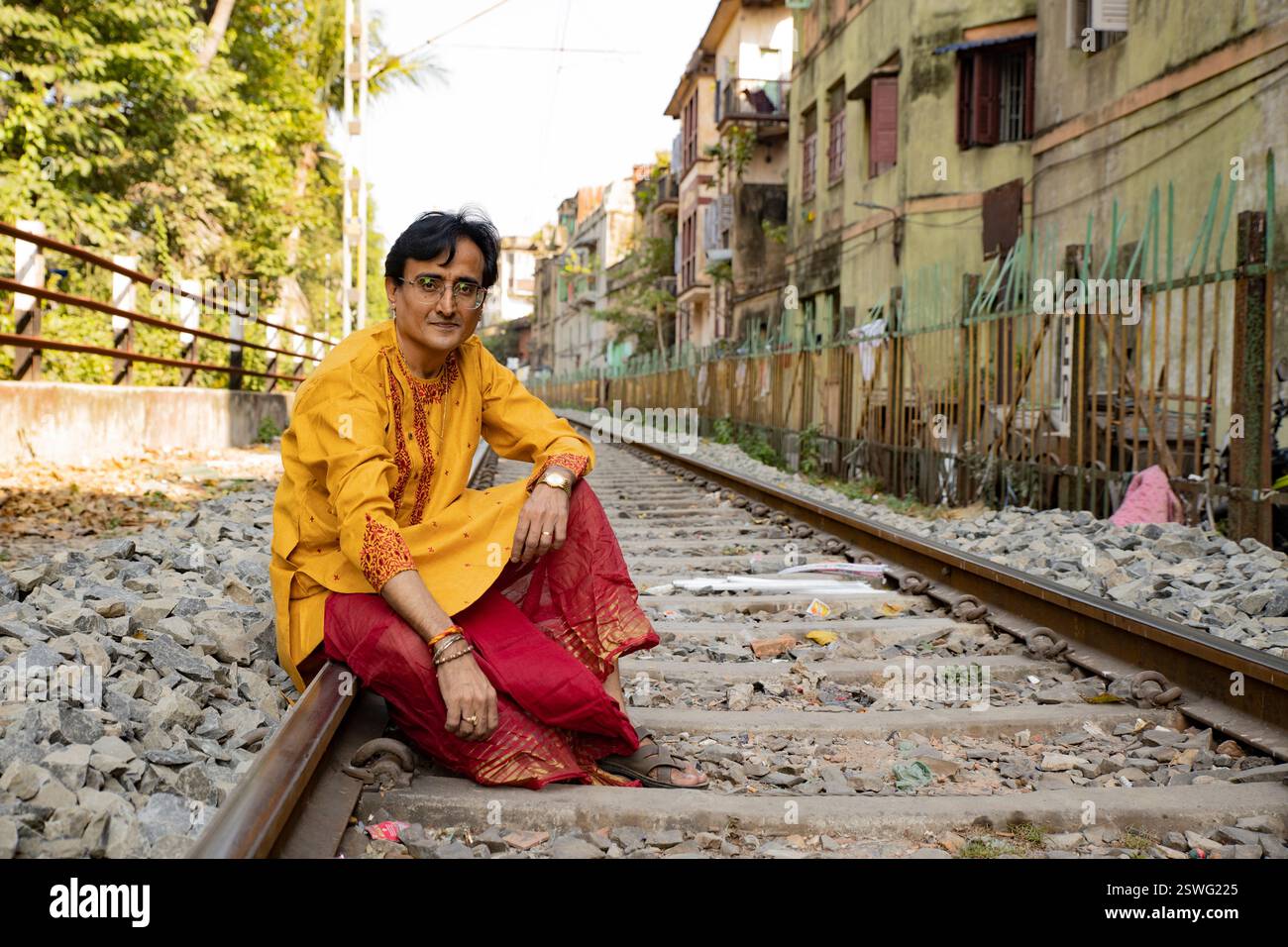 Un indien portant un dhoti rouge bengali traditionnel indien et kurta orange posant en plein air dans les rues de kolkata Banque D'Images