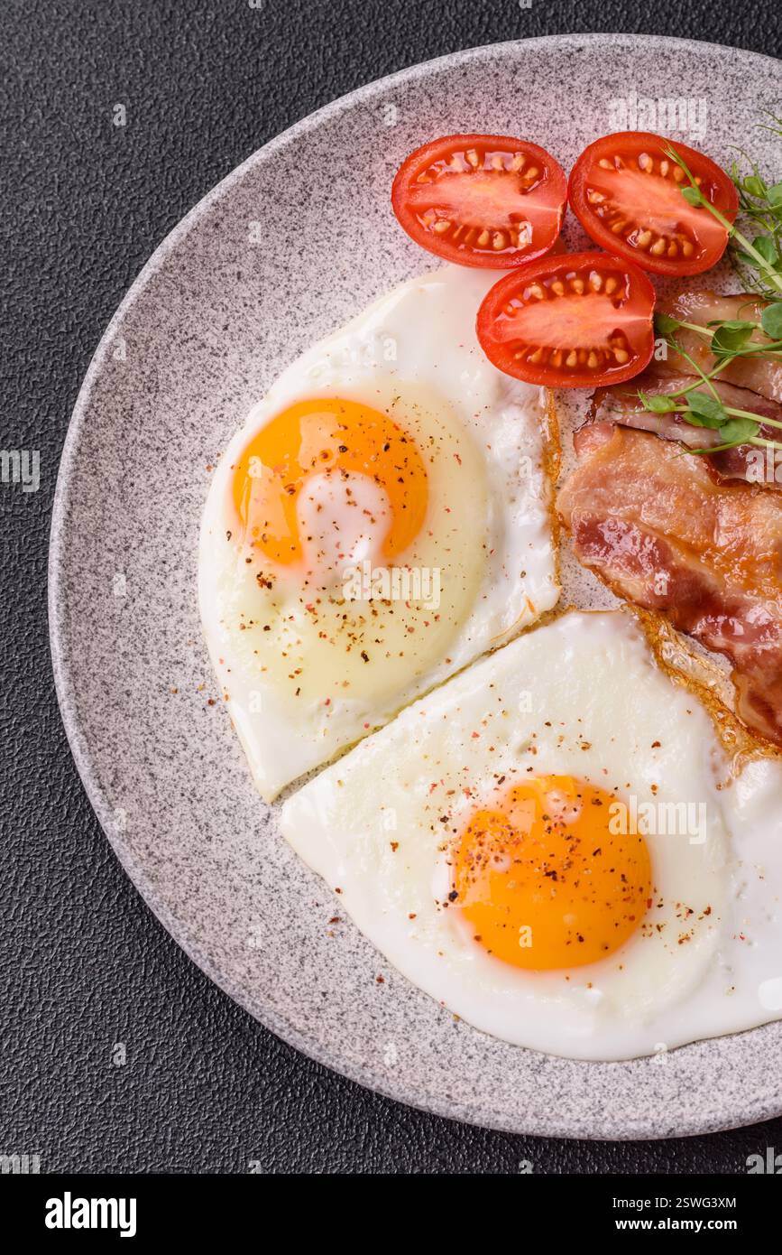 Un petit déjeuner copieux avec œufs au plat, bacon, tomates, microgreens Banque D'Images
