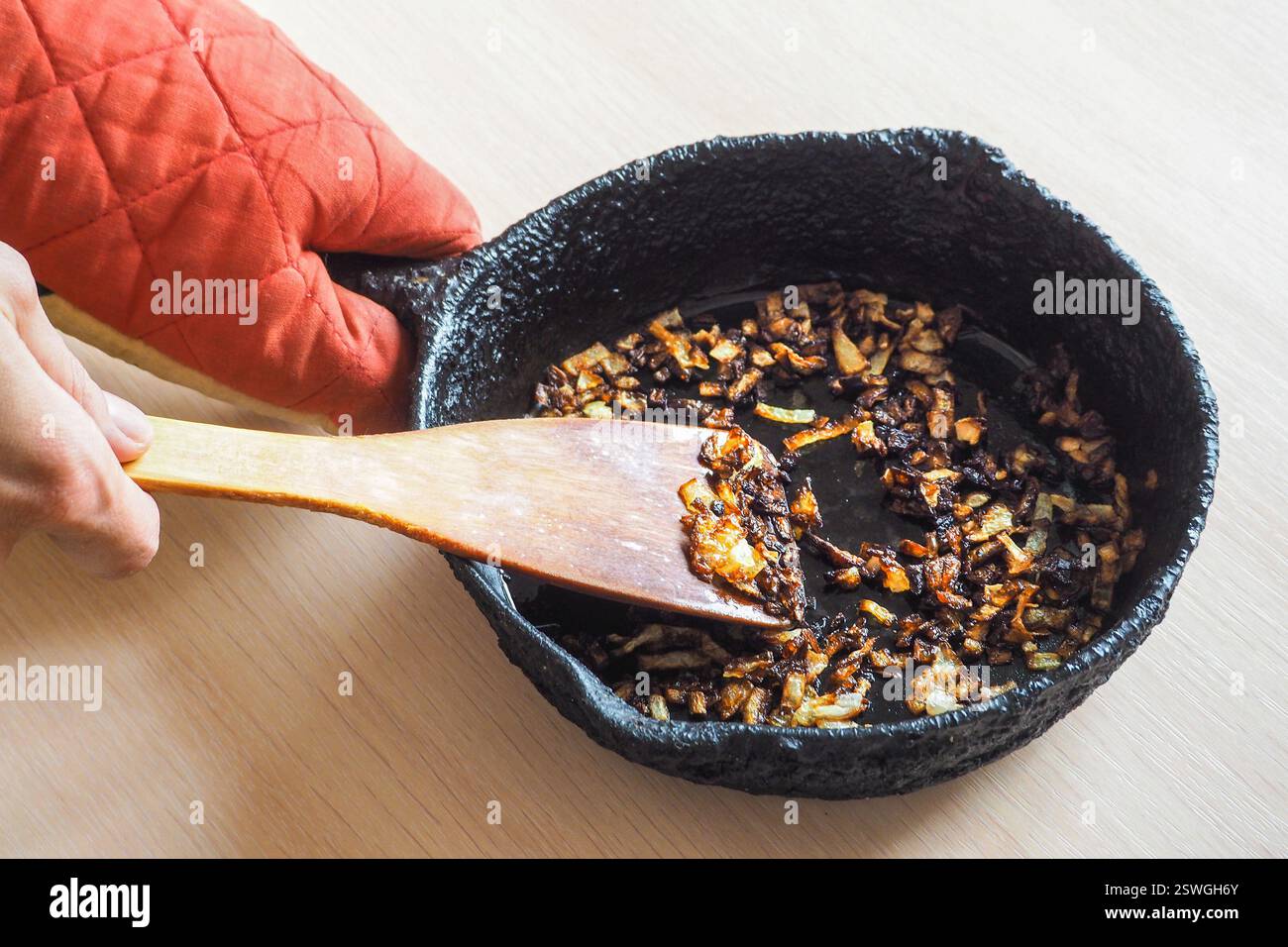 Oignon trop cuit dans une poêle. Une mauvaise cuisine. Le concept d'aliments nocifs et cancérigènes. Banque D'Images