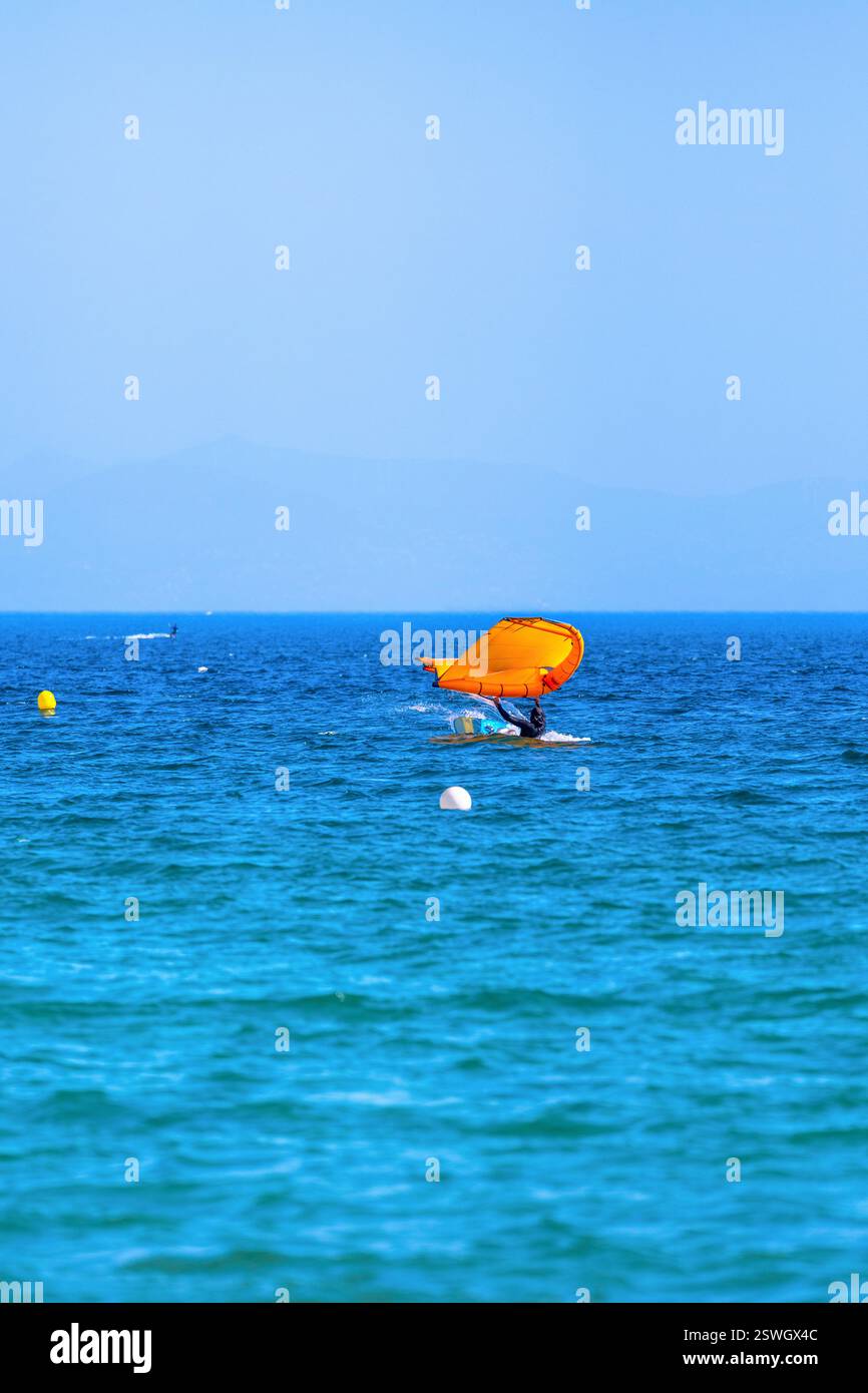 Athlète de fleuret d'aile tombant dans l'océan avec une aile orange près de Tarifa, Espagne. Banque D'Images