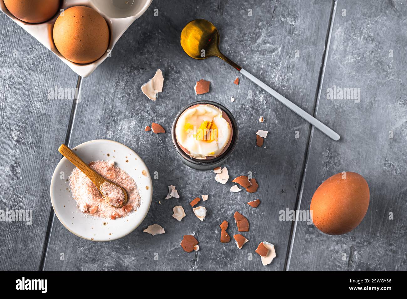 Oeuf brun bouilli où le dessus est coupé dans un coquetier gris sur fond gris, espace de copie Banque D'Images