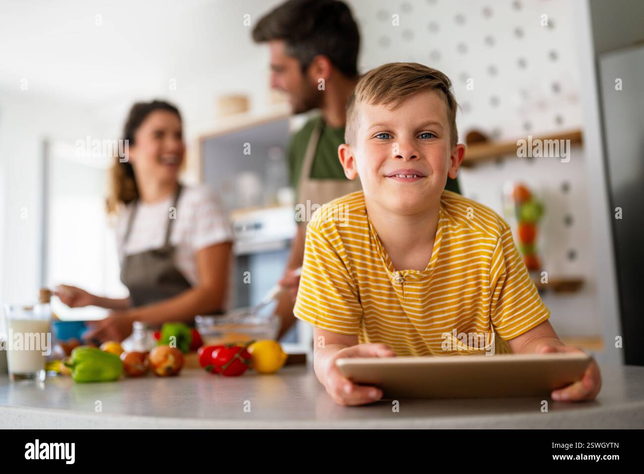 Famille heureuse avec enfant s'amusant en utilisant la tablette ensemble, les parents et l'enfant riant se relaxant à la maison Banque D'Images