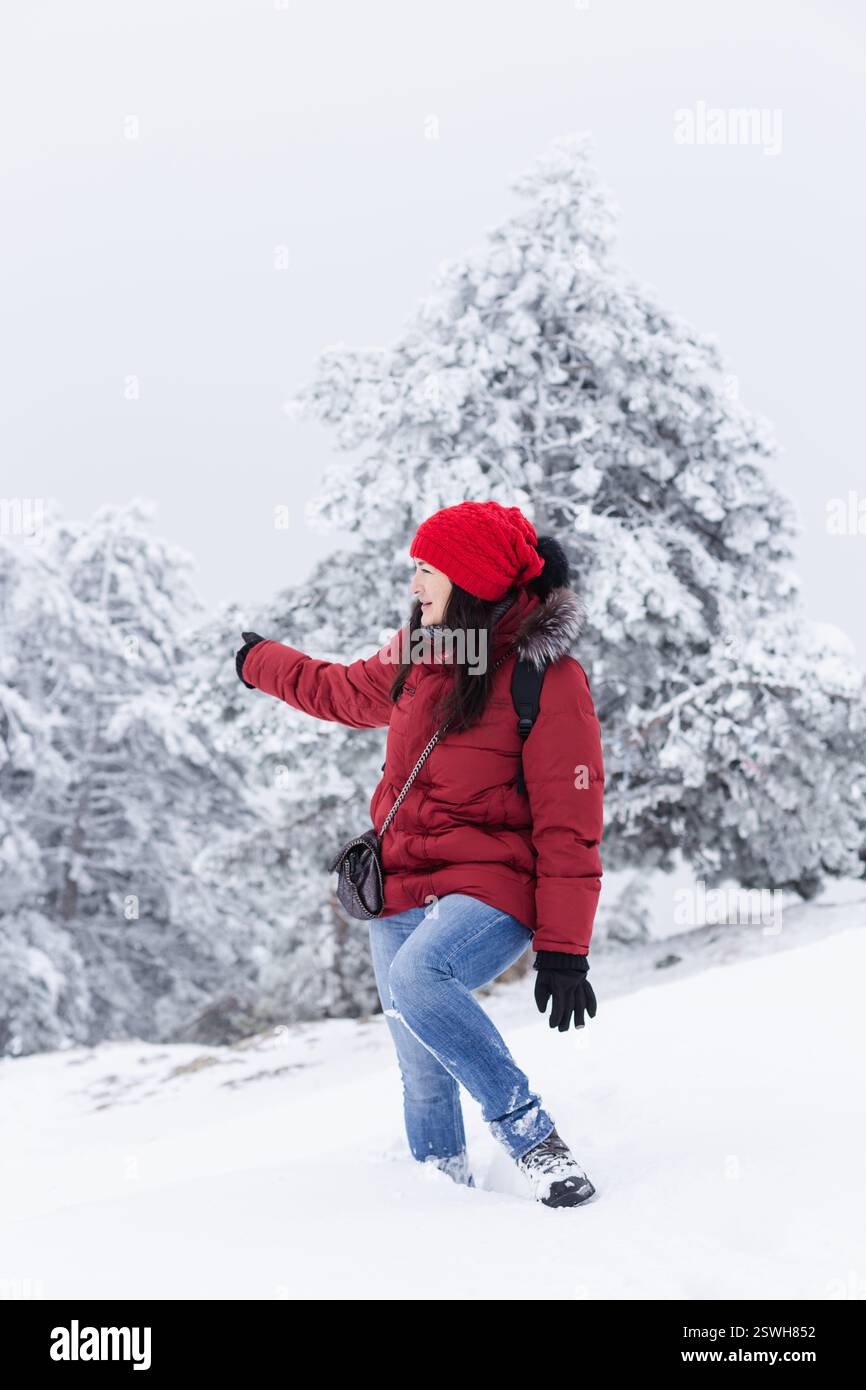 Femme mi-adulte randonneur pointant vers des pins couverts de neige Banque D'Images