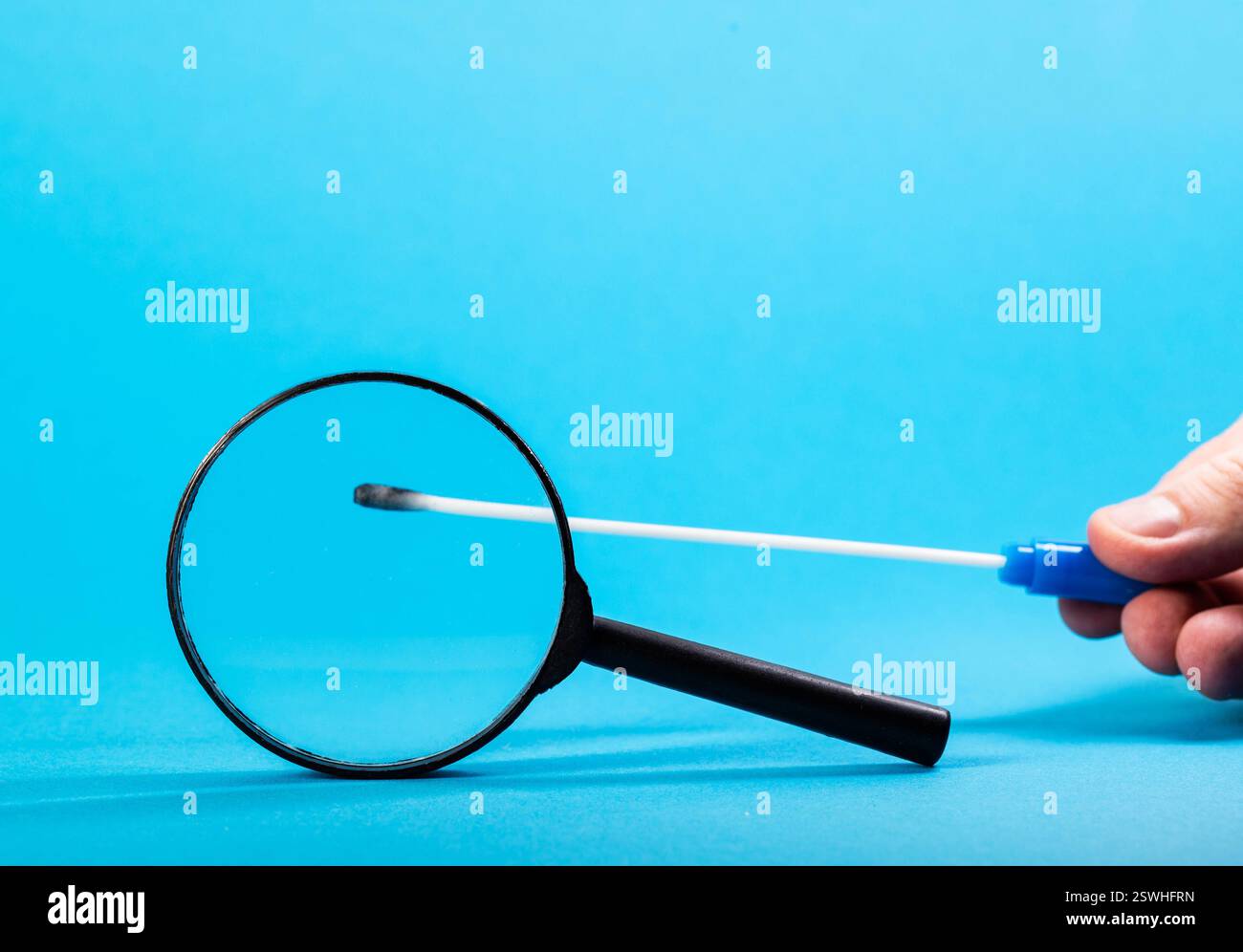 médecin allergologue tient une sonde stérile avec des tests d'allergie contre une loupe sur un fond bleu. Concept de diagnostic d'allergie pour plante po Banque D'Images