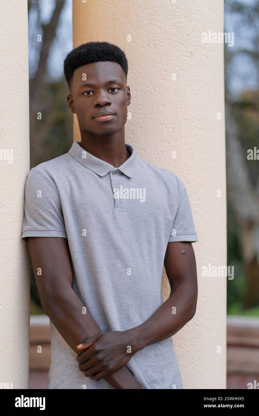 Un homme debout et appuyé contre un pilier avec sa main placée avec confiance sur sa hanche, à Bilbao. Banque D'Images