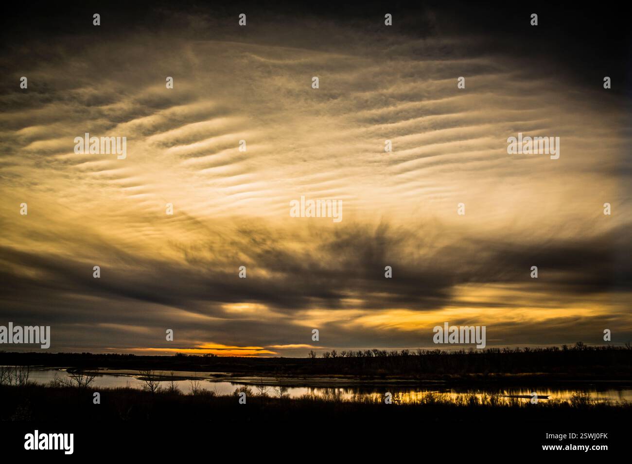 Grand nuage dans le ciel avec un soleil en arrière-plan. Le ciel est nuageux dans l'ensemble. Le soleil se couche Banque D'Images