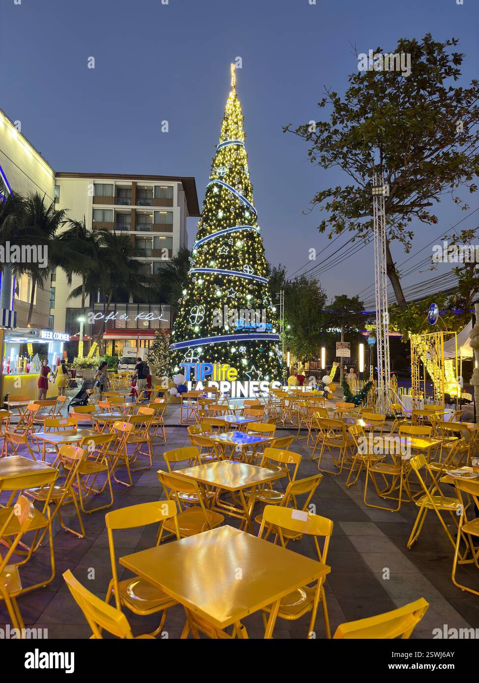 Hua Hin, Thaïlande - 1er janvier 2024, arbre de Noël se dresse haut sur une place de la ville, entouré de tables et de chaises jaunes Banque D'Images