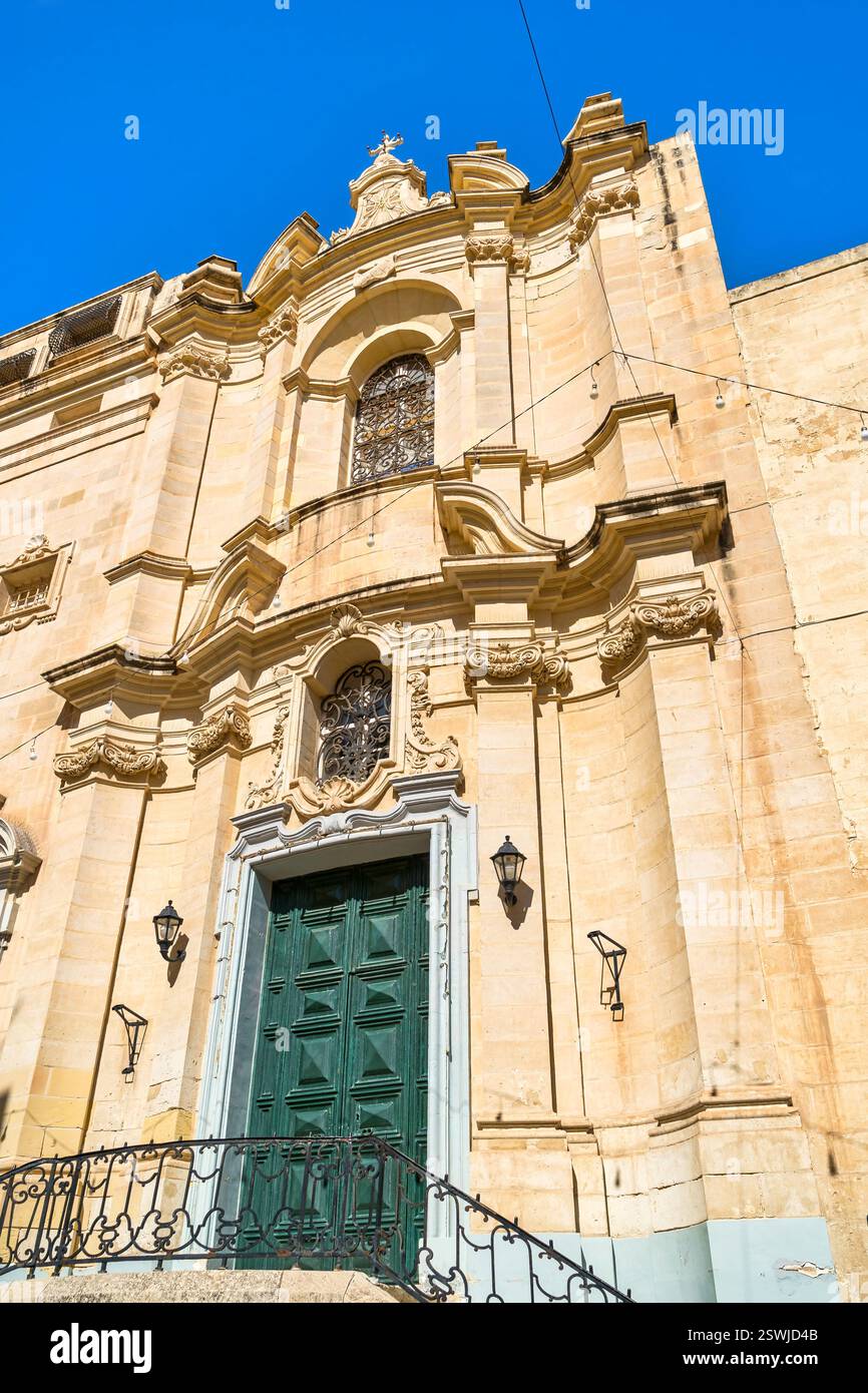 Façade d'église baroque avec portes vertes et pierres ornées - la Valette, Malte. Banque D'Images