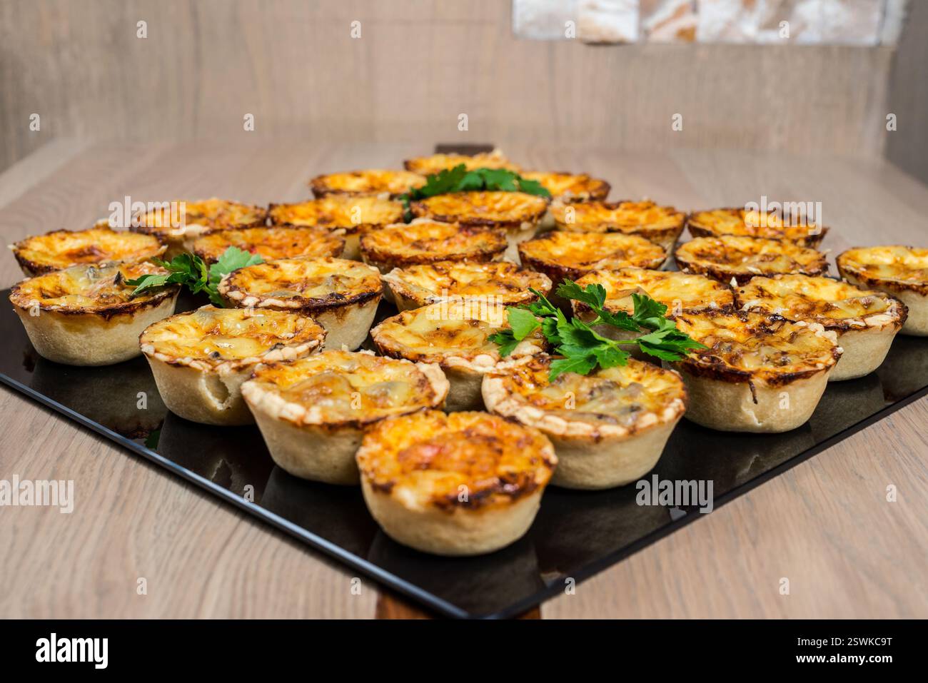 Mini quiches assorties sur plateau : tartes salées de la taille d'une bouchée avec diverses garnitures parfaites pour les fêtes ou les collations Banque D'Images