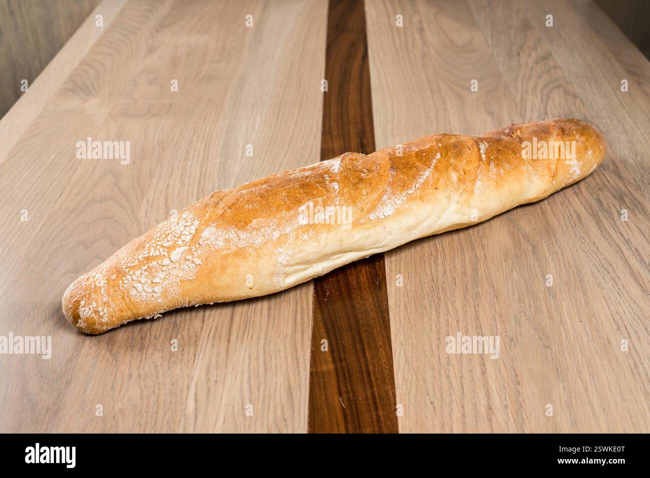 Baguette brun doré sur une surface en bois aux tons neutres cuite à la perfection et prête à être appréciée Banque D'Images
