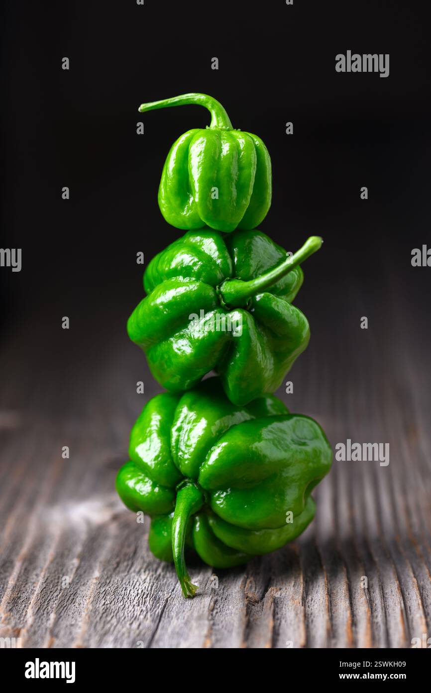 Trois poivrons habanero verts mûrs (capsicum chinense) sur une table en bois. Poivrons mexicains très chauds sur la table en bois rustique de près Banque D'Images