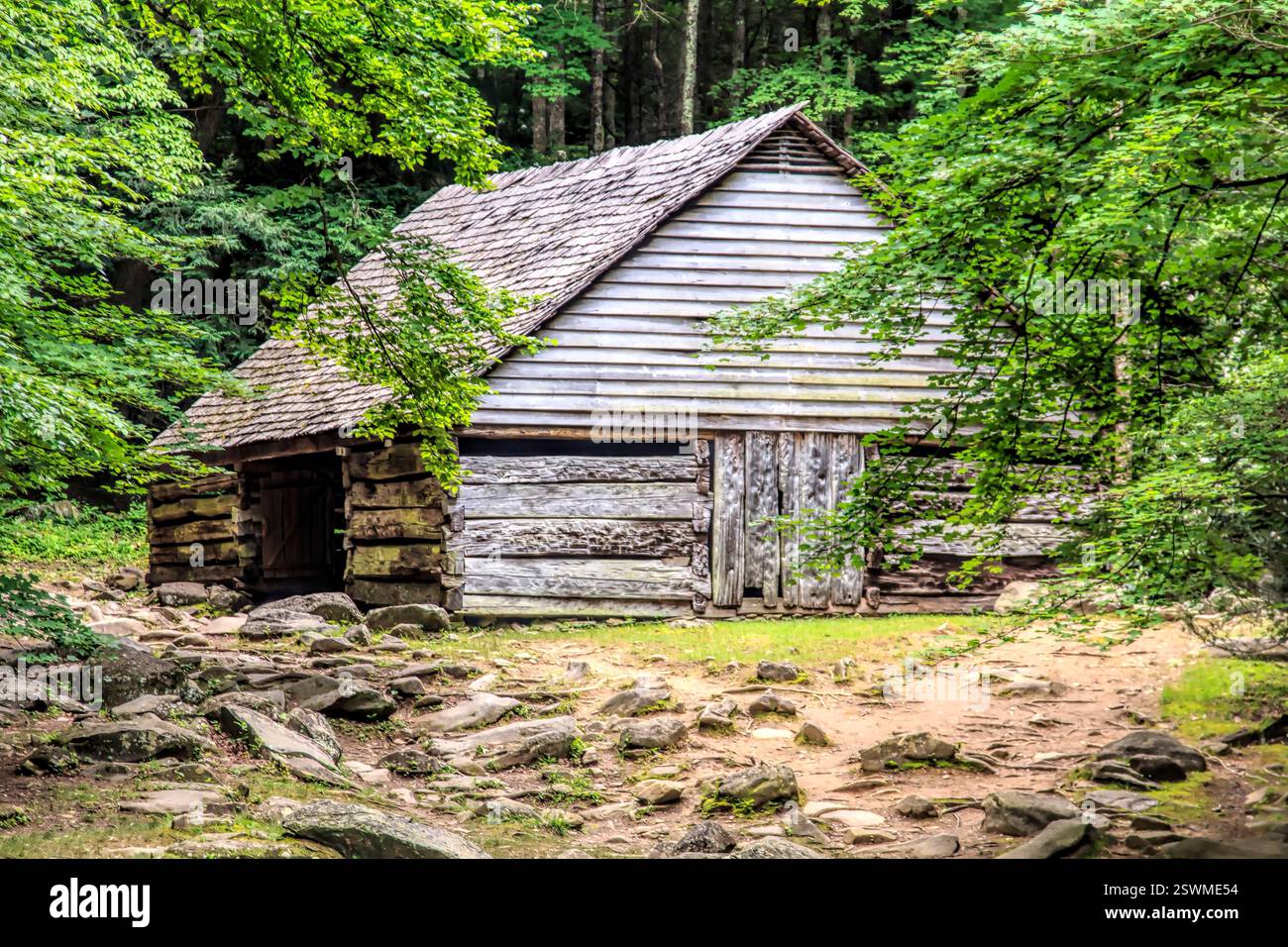 Petite cabane en rondins avec toit incliné. Le toit est en bois. La cabine est entourée de rochers Banque D'Images
