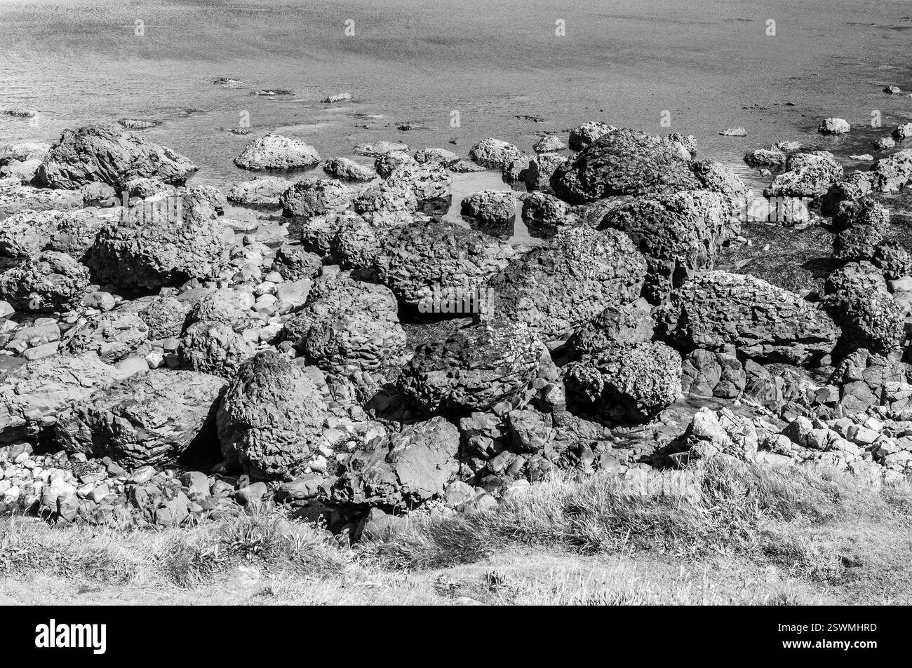 Un rivage rocheux avec un grand tas de rochers. Les roches sont dispersées et certaines sont plus grandes que d'autres. La scène est désolée et stérile, sans signes Banque D'Images