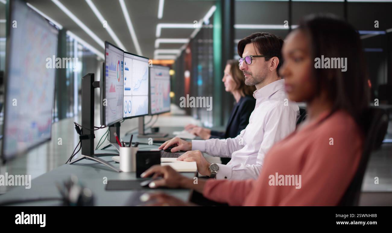 Groupe diversifié d'étudiants et d'enseignants analysant les analyses commerciales sur des écrans. Banque D'Images