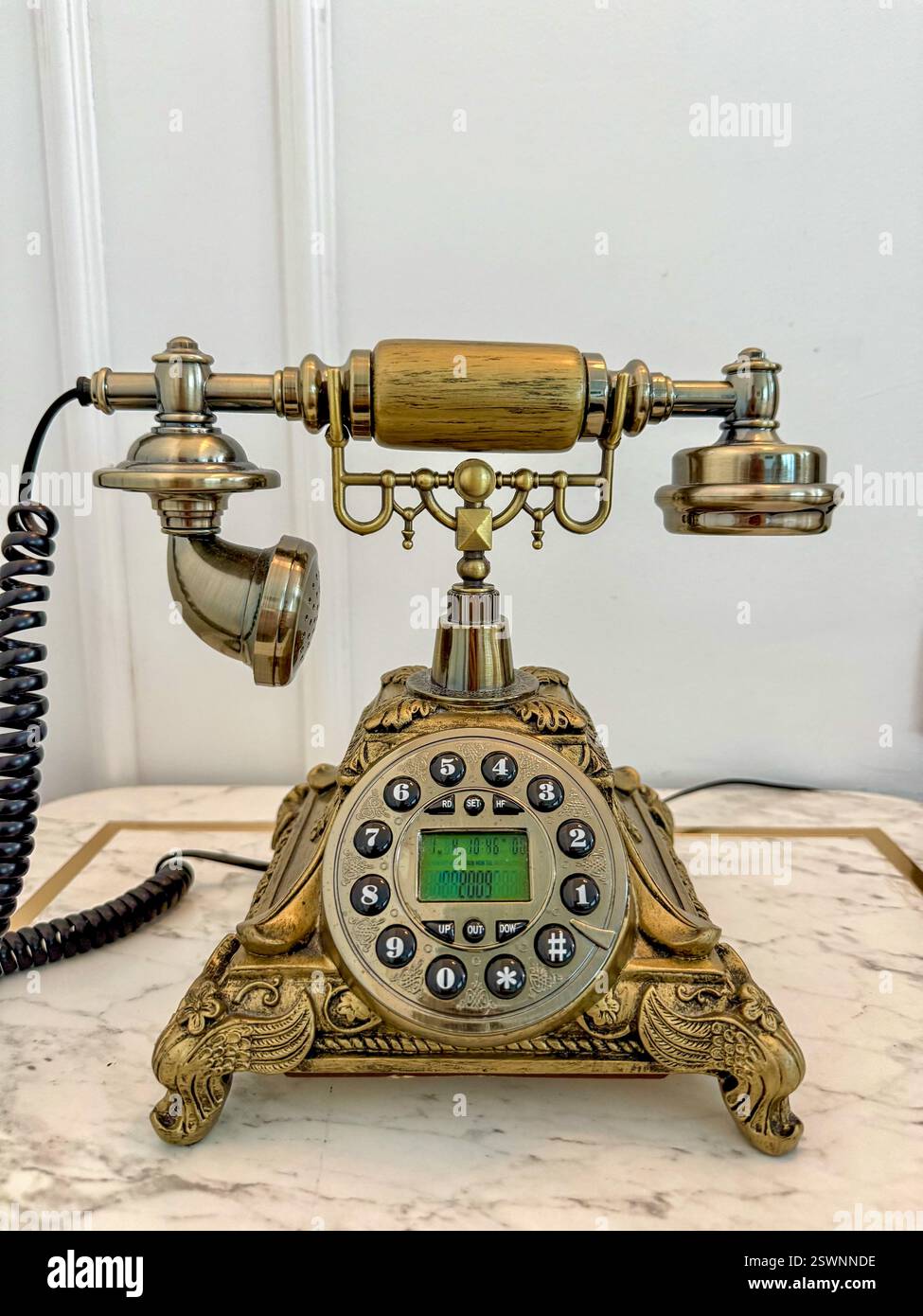 Téléphone en laiton vintage avec cadran numérique moderne Un téléphone en laiton vintage doté d'un cadran numérique de mode, placé sur une table en marbre. - Image de stock capturée avec un smartphone