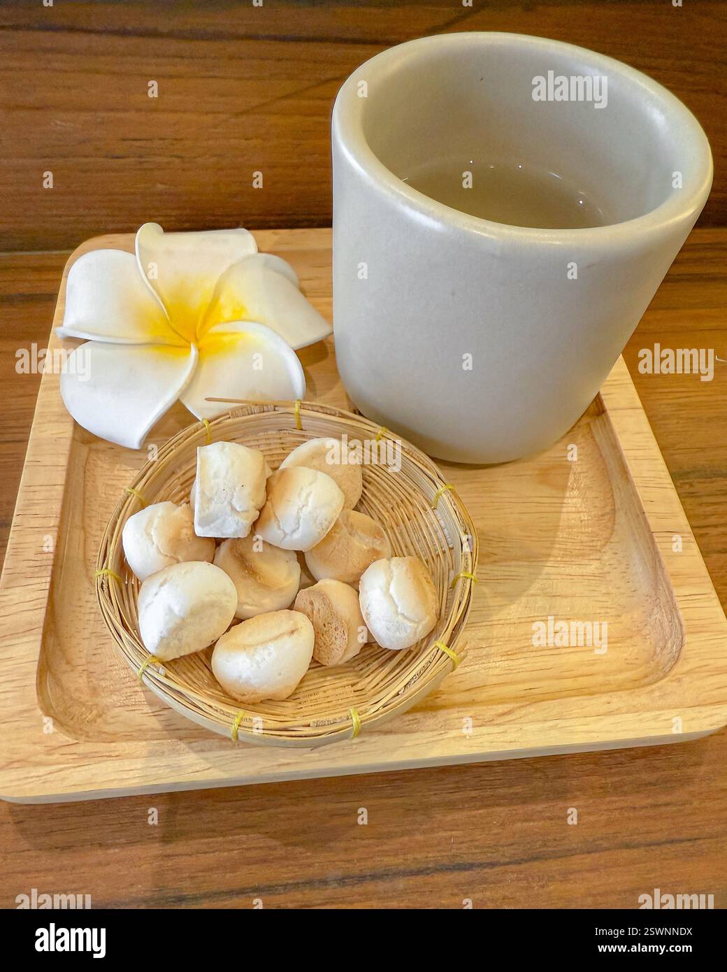 Thé et biscuits faits à la main sur un plateau en bois Un plateau en bois naturel avec une tasse en céramique remplie d'une boisson chaude, accompagnée de biscuits faits à la main Banque D'Images