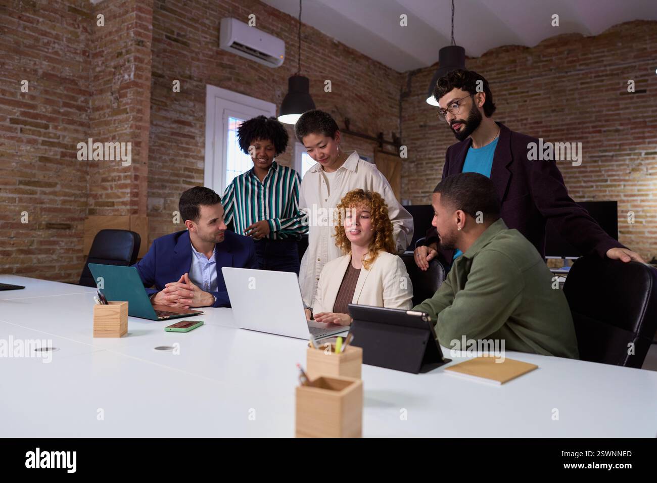 Équipe de marketing travaillant ensemble sur le projet en utilisant un ordinateur portable dans le bureau moderne Banque D'Images