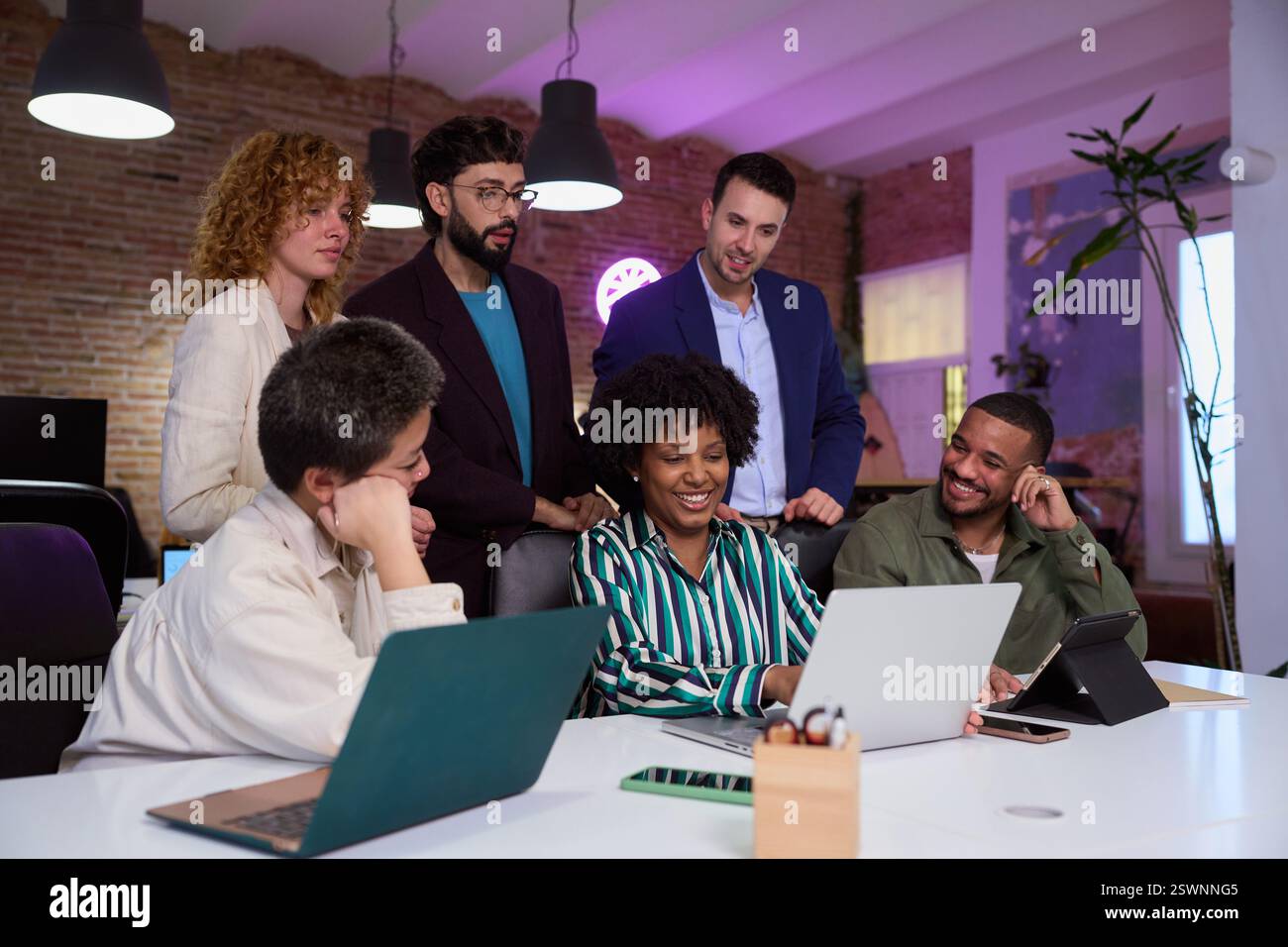 Équipe d'affaires diversifiée collaborant sur le projet à l'aide d'un ordinateur portable dans un bureau moderne Banque D'Images