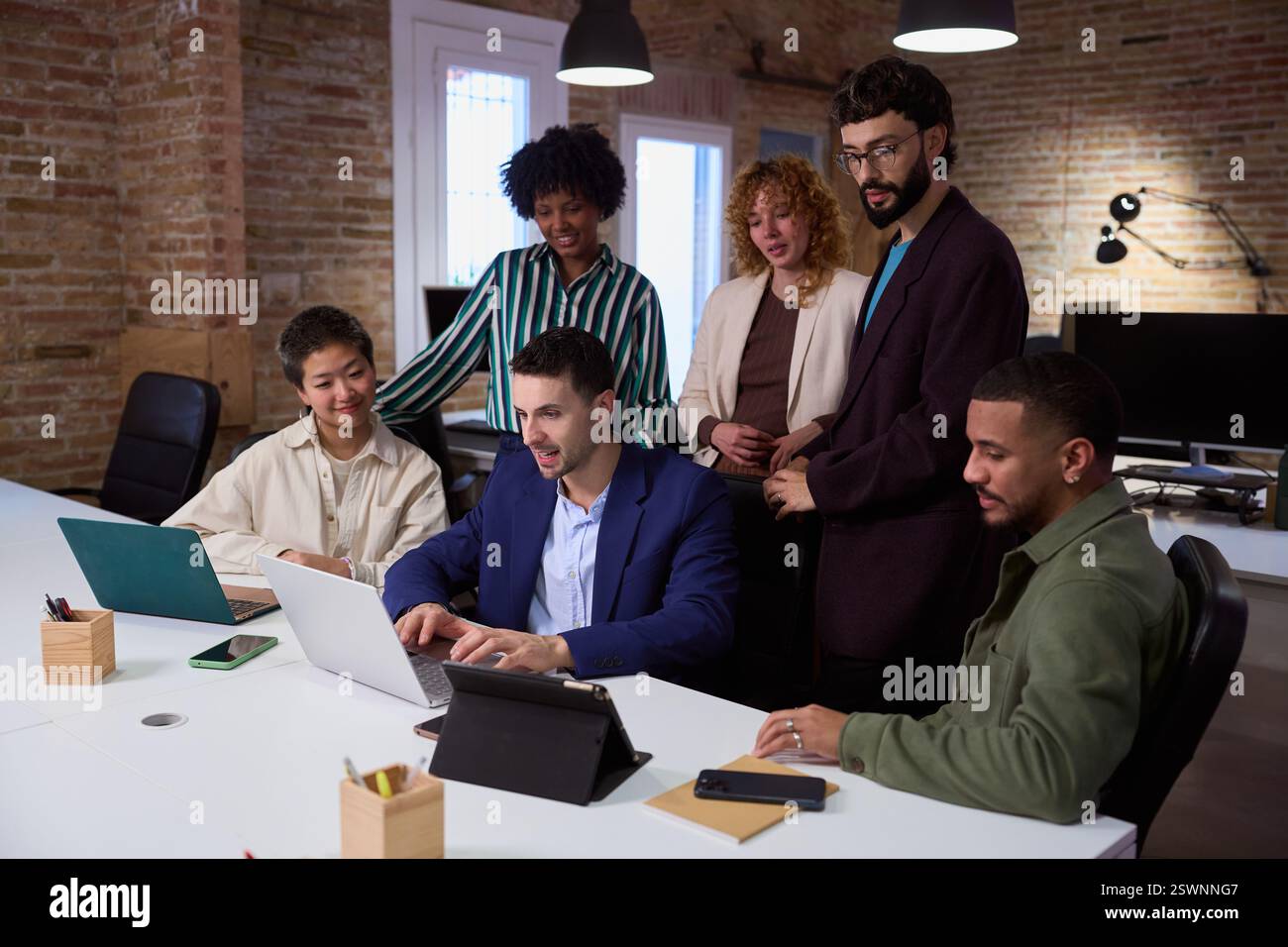 Équipe de marketing travaillant ensemble sur le projet en utilisant un ordinateur portable dans le bureau moderne Banque D'Images
