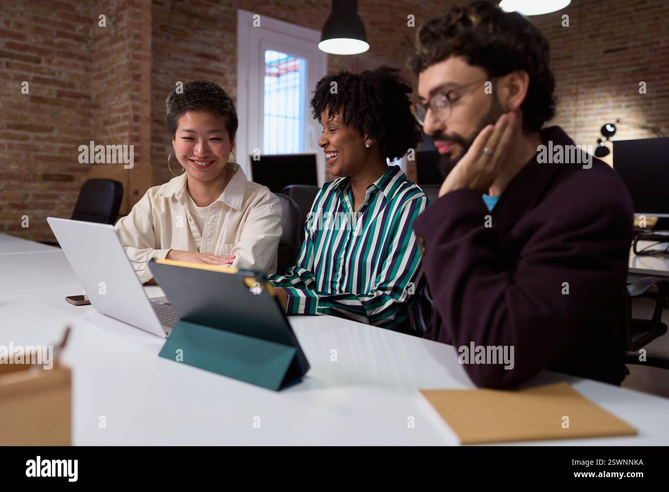 Équipe marketing travaillant ensemble sur un projet en utilisant un ordinateur portable et une tablette au bureau Banque D'Images