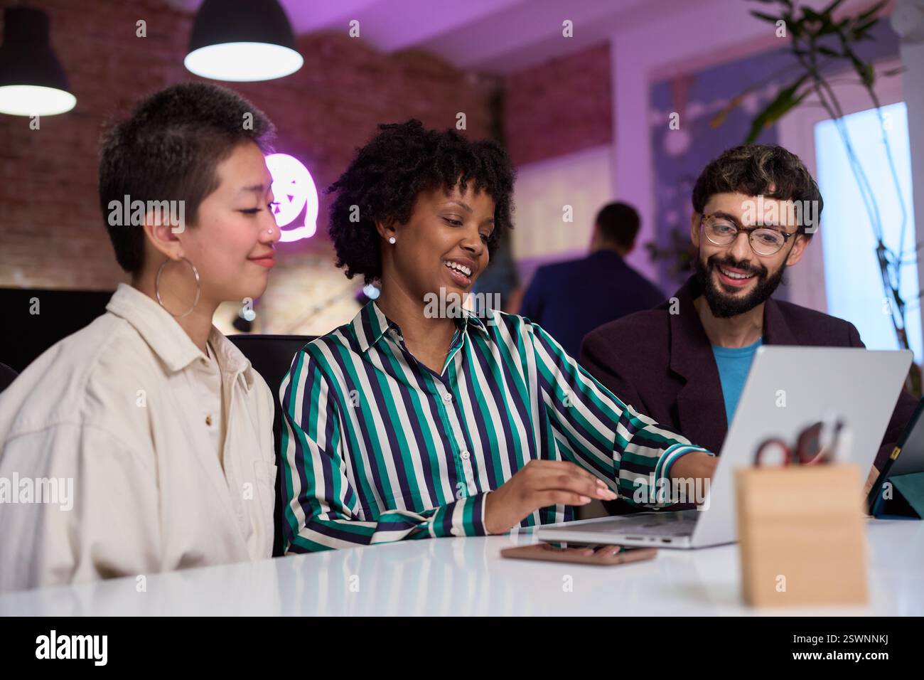 Équipe marketing travaillant ensemble sur un ordinateur portable dans un bureau moderne Banque D'Images