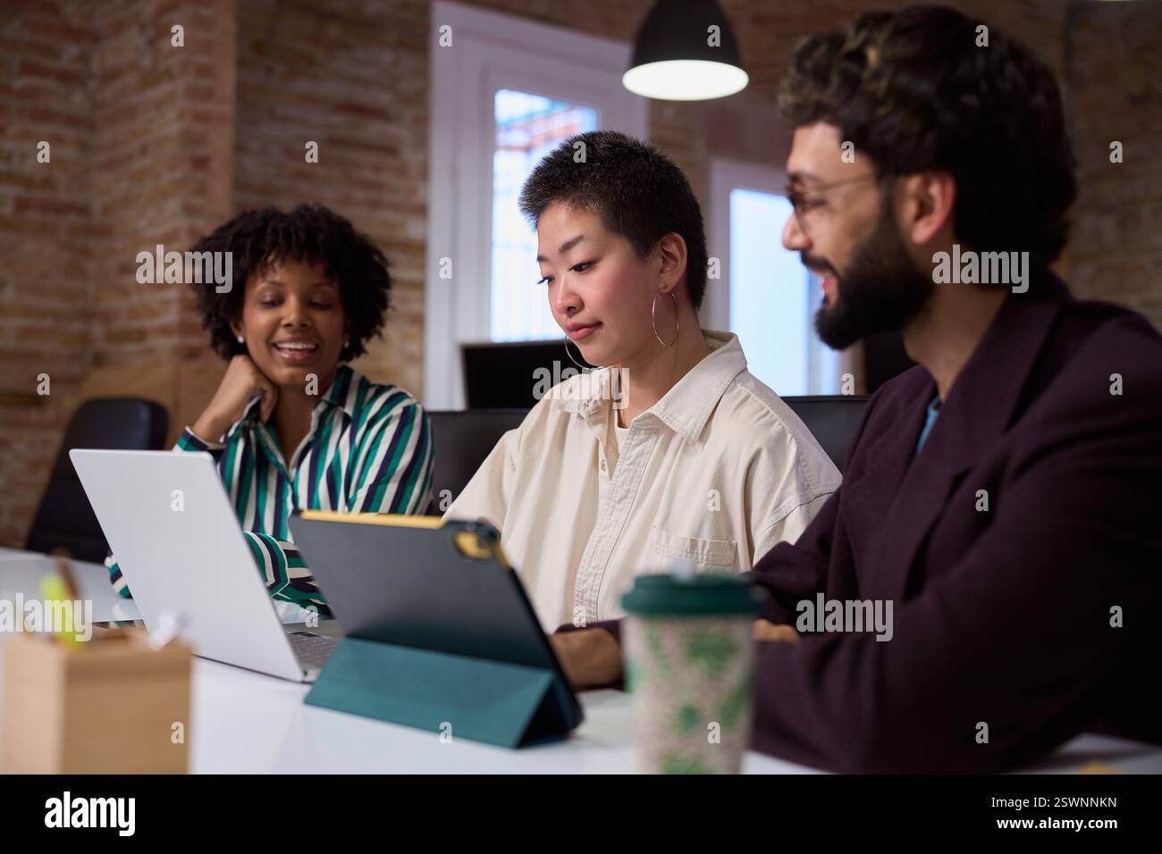 Équipe marketing travaillant ensemble sur des appareils dans un bureau moderne Banque D'Images
